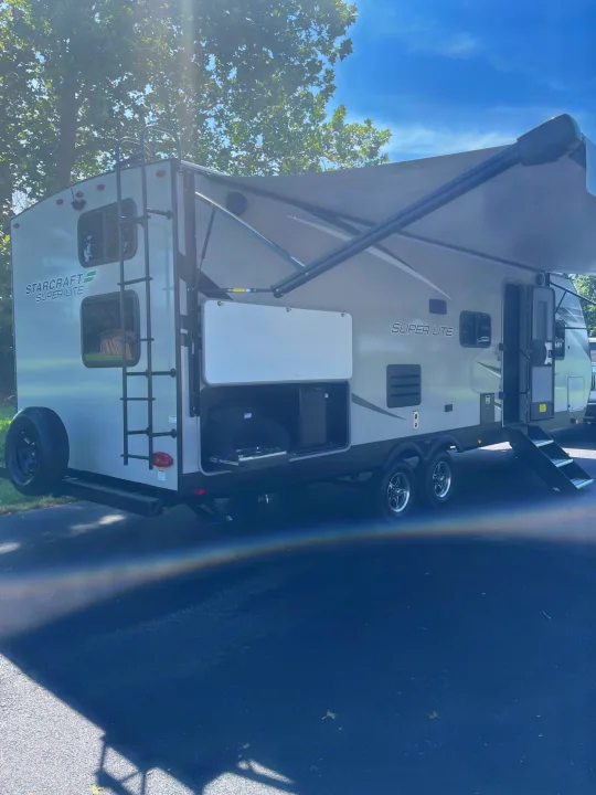 Grey Starcraft Super Lite travel trailer with extended awning, outdoor kitchen, and steps, ideal for an rv rental.. Starcraft Super Lite 2022
