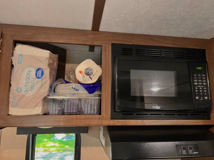 RV rental kitchen: Organized upper cabinet with paper products, microwave, and Heng's range hood visible.. Keystone RV Hideout 2019
