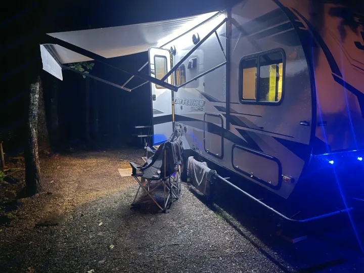 Nighttime at an RV rental campsite: Illuminated camper, awning out, chairs ready for a relaxing evening.. Jayco Jay Feather Micro 2022