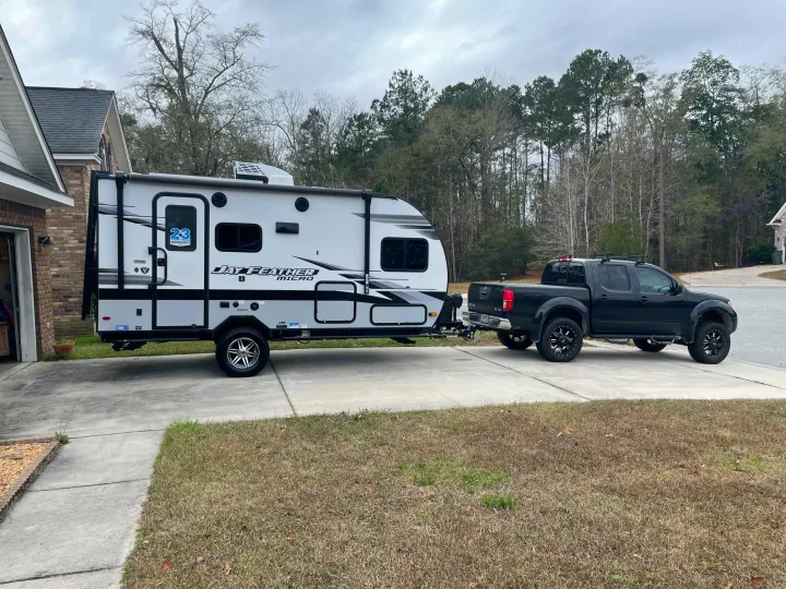 White travel trailer (RV rental) hitched to a black pickup truck on a driveway, ready for its next journey.. Jayco Jay Feather Micro 2022