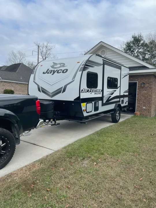 Jayco Jay Feather Micro travel trailer RV rental hitched to a black pickup truck on a driveway next to a house.. Jayco Jay Feather Micro 2022