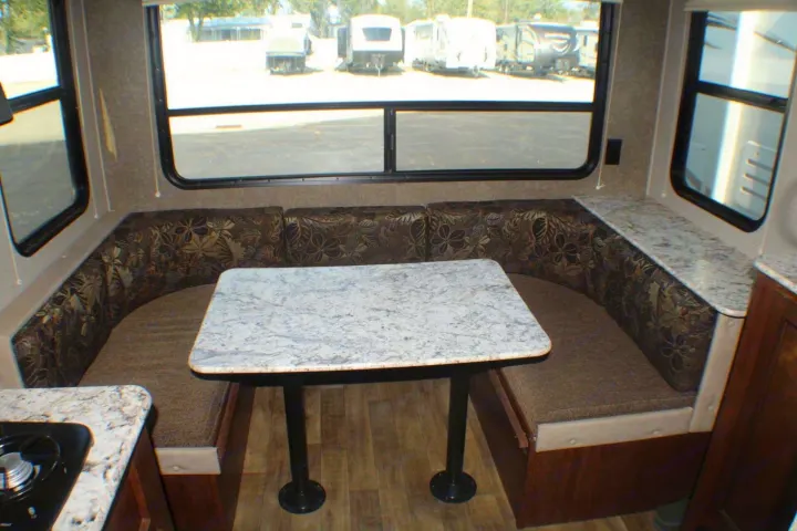 Cozy U-shaped dinette with a table, comfortable bench seating, and wide windows inside this rv rental for dining.. Keystone RV Hideout LHS Mini 2018