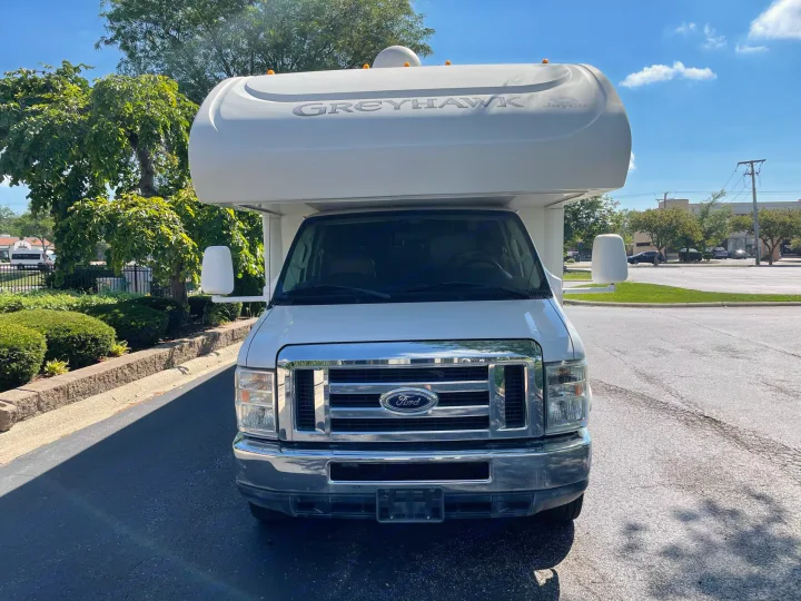 Front view of a white Jayco Greyhawk Class C RV, built on a Ford chassis, parked outdoors. Great for your next rv rental adventure.. Jayco Greyhawk 2013