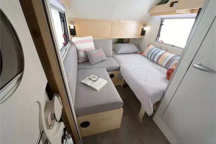 View inside a modern RV rental featuring an L-shaped sofa, convertible bed, and clever storage solutions.. Nucamp TAB 320 CS-S 2022