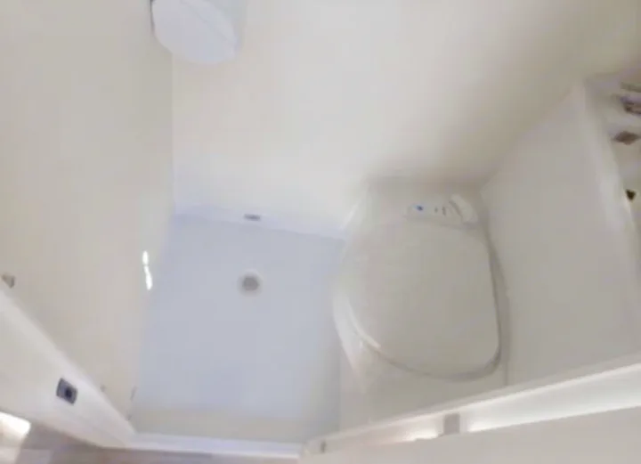 An RV rental's compact bathroom, showing a white toilet and a separate shower area with a floor drain.. Nucamp TAB 320 CS-S 2022