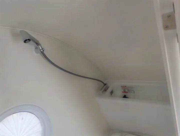 Compact shower and basin in an RV rental bathroom, featuring a flexible shower head and a round window.. Nucamp TAB 320 CS-S 2022
