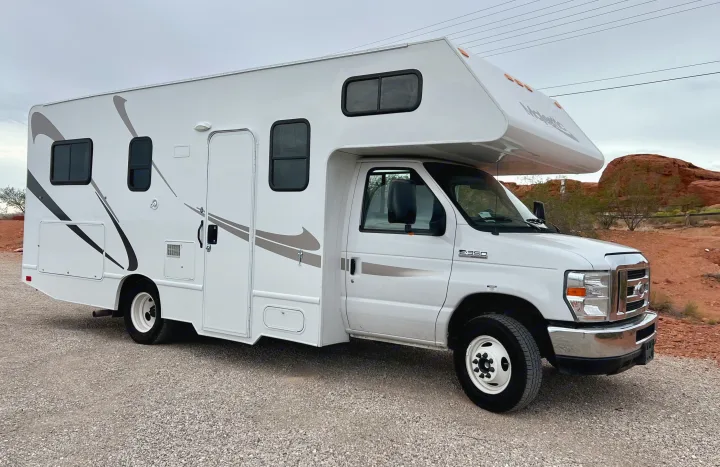 White Class C RV rental parked on gravel near red rock formations, ready for your next motorhome adventure.. Thor Majestic 2018