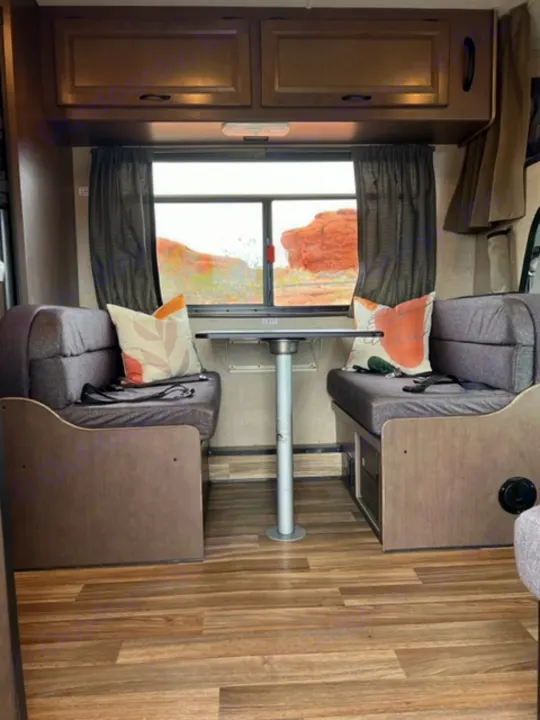 RV rental dinette area with wood floors, storage, and a window view of red rock landscape.. Thor Majestic 2018