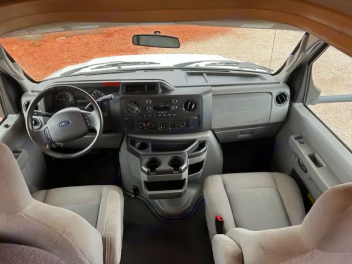 Explore the roomy interior of this Ford RV rental. The cockpit features a functional dashboard, steering wheel, and two front seats.. Thor Majestic 2018