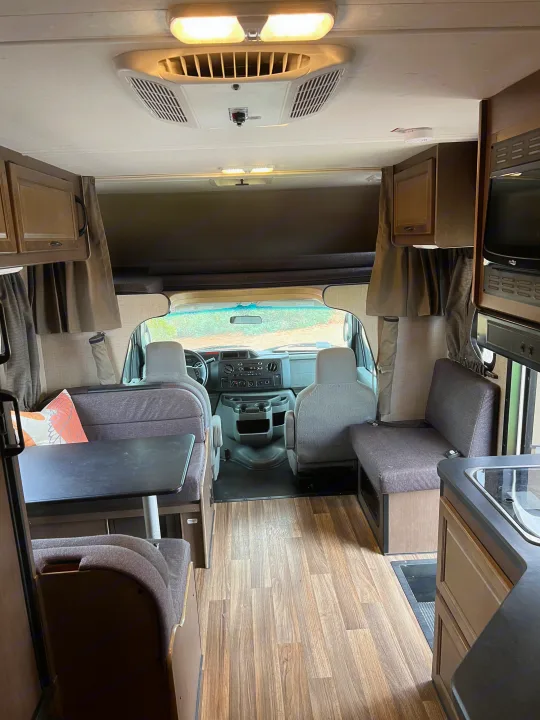 Inside a spacious RV rental, highlighting the dining area, kitchen, and front driving cab. Perfect for road trip adventures.. Thor Majestic 2018