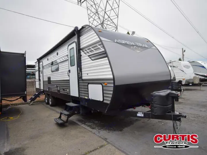 A grey Aspen Trail travel trailer, ready for your next RV rental adventure, shown with steps and awning.. Aspen Trail Aspen Trail Trailer 2021