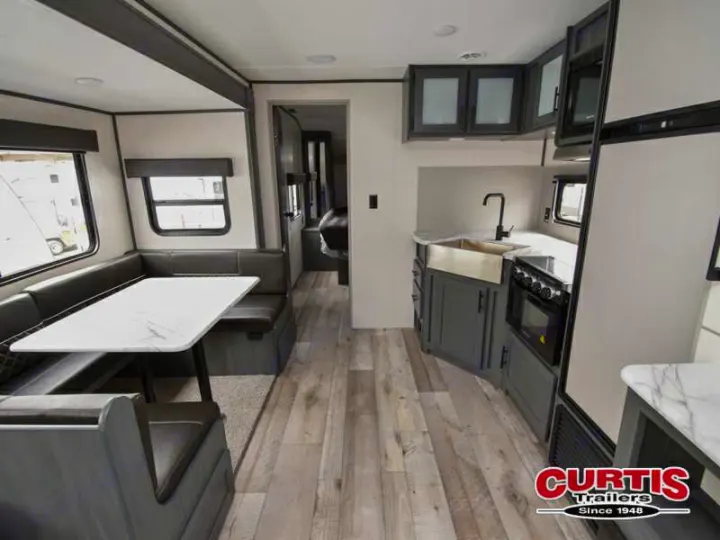 Spacious RV rental interior features a modern kitchen with sink and stove, plus a comfortable U-shaped dinette.. Aspen Trail Aspen Trail Trailer 2021