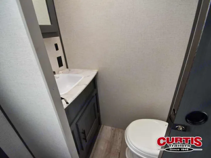 View inside an RV rental showing a small, well-lit bathroom with a white sink, dark vanity, and toilet.. Aspen Trail Aspen Trail Trailer 2021