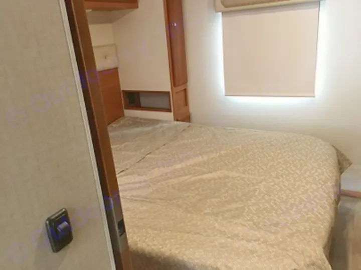 Inside an RV rental: a practical bedroom with a neatly made bed, window shade, and built-in cabinetry.. Winnebago Vista 2017