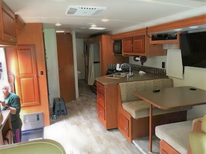 This RV rental interior features a kitchen, dinette, and hallway, offering comfort for road trips.. Winnebago Vista 2017