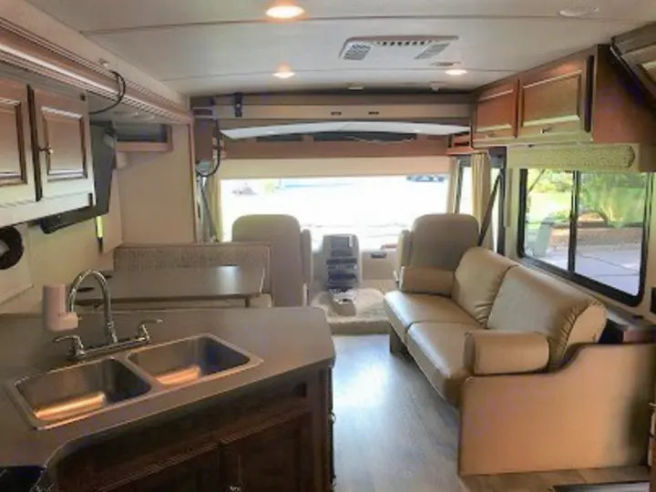 Spacious rv rental interior: kitchen with sink, dinette, and living area with sofa, looking towards driver's cabin.. Winnebago Vista 2017