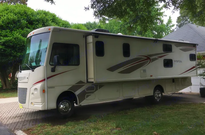 Cream Winnebago Vista RV rental, with a slide-out extended, parked on a paved area, ready for adventure.. Winnebago Vista 2017