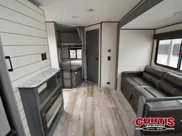 Explore this RV rental's modern interior: a living area with dark sofa, fireplace, and bunk beds for a comfortable travel experience.. Aspen Trail Aspen Trail Trailer 2021