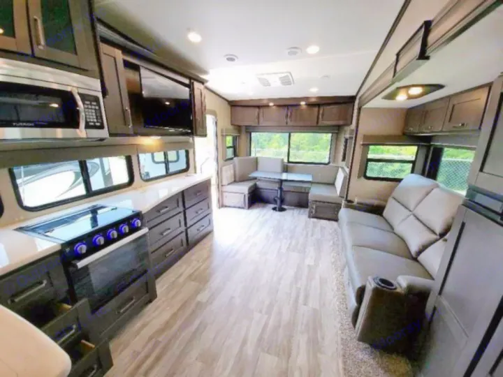Inside a comfortable rv rental: a full kitchen, a dining booth, and a living area with a sofa & recliners. Spacious interior.. Grand Design Reflection 2021