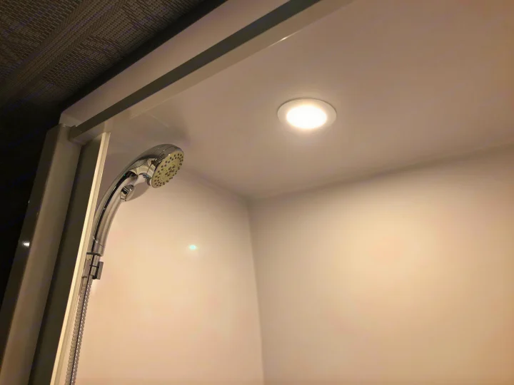 RV rental shower: Brightly lit, compact white interior with a chrome shower head and recessed ceiling light.. Mercedes Sprinter 2022