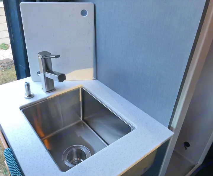 Modern kitchen in an RV rental with a stainless steel sink, sleek faucet, and white speckled countertop. Compact and functional.. Mercedes Sprinter 2022