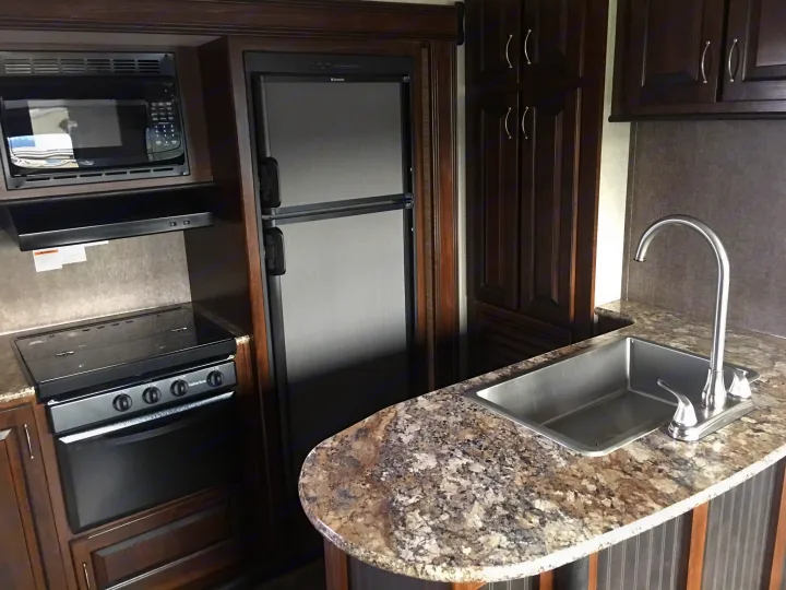 Modern RV rental kitchen with microwave, oven/stove, fridge, and sink. Equipped for comfortable travel cooking.. Heartland Torque 2017