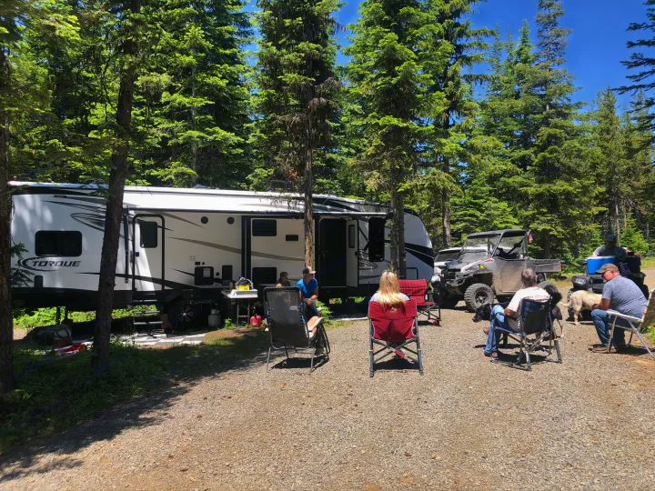 Enjoying an RV rental adventure: people, dogs, and an off-road vehicle at a sunny forest campsite.. Heartland Torque 2017