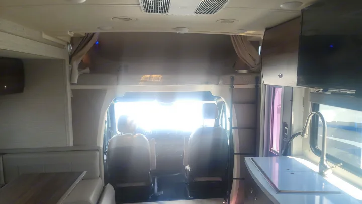 Spacious RV rental interior with dinette, front cab, overhead bunk, and kitchenette, perfect for road trips.. Winnebago Navion 2022
