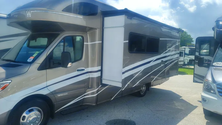Spacious grey & white Class C motorhome with an extended slide-out, ideal for an RV rental. Parked outdoors.. Winnebago Navion 2022