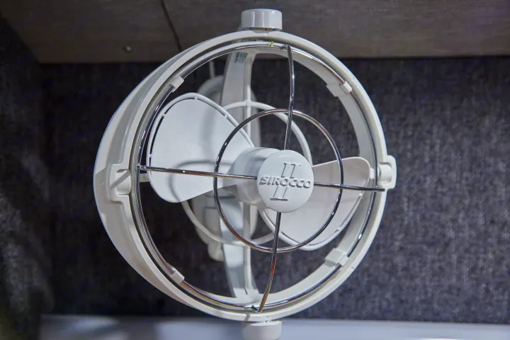 A white Sirocco fan, often found in an RV rental, is mounted on a textured gray wall, providing air circulation.. Chevrolet silverado 2500 2022