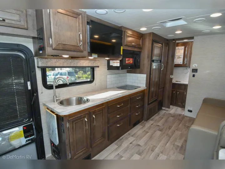 Modern RV rental interior with compact kitchen, including sink, stove, microwave, fridge, and cozy living area.. Jayco 24M 2022