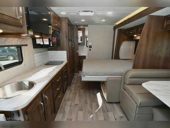 Explore this modern RV rental interior featuring a well-equipped kitchen, pull-down bed, and cozy dinette.. Jayco 24M 2022