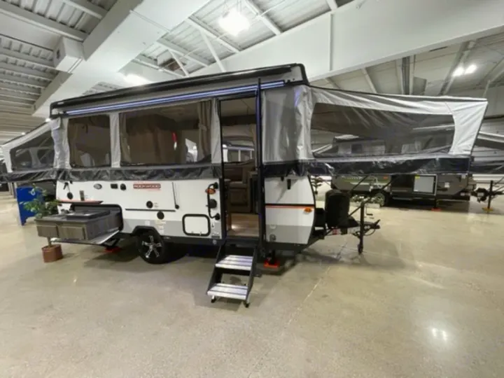 This pop-up RV rental, extended in a showroom, showcases spacious camping adventures.. Forest River Rockwood Premier 2022