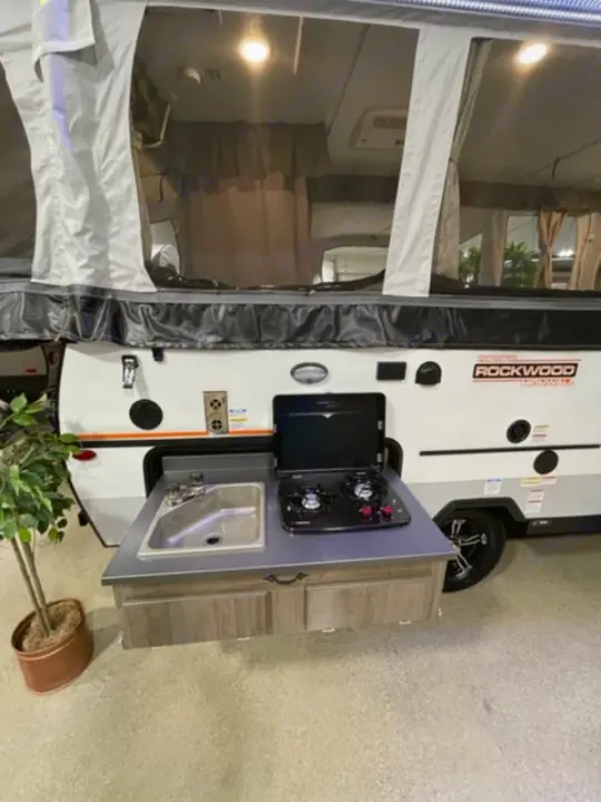 This pop-up camper RV rental features a convenient pull-out outdoor kitchen with a sink and stove.. Forest River Rockwood Premier 2022