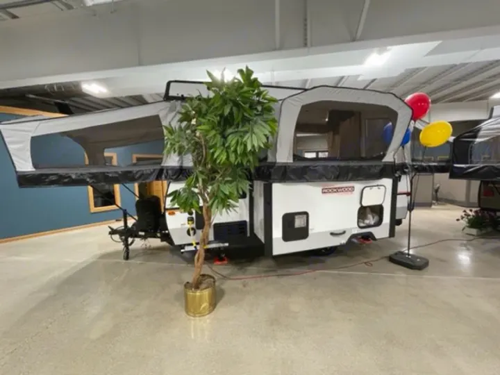 White and gray Rockwood pop-up RV rental fully extended indoors, showcasing its camping setup with two bed areas.. Forest River Rockwood Premier 2022