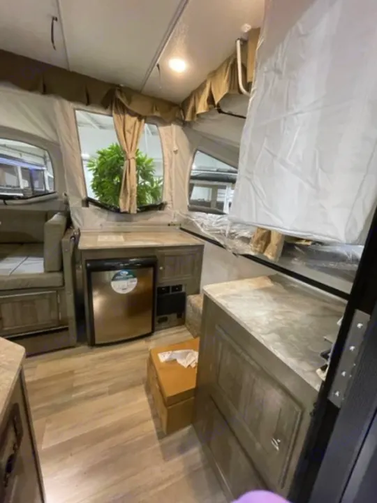 Experience RV rental comfort: a compact pop-up camper interior with kitchen counter, mini-fridge, and convertible bed.. Forest River Rockwood Premier 2022