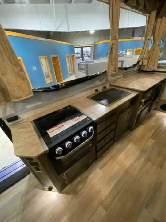 RV rental pop-up camper kitchen with stove, sink, and cabinets. View of a spacious showroom interior.. Forest River Rockwood Premier 2022