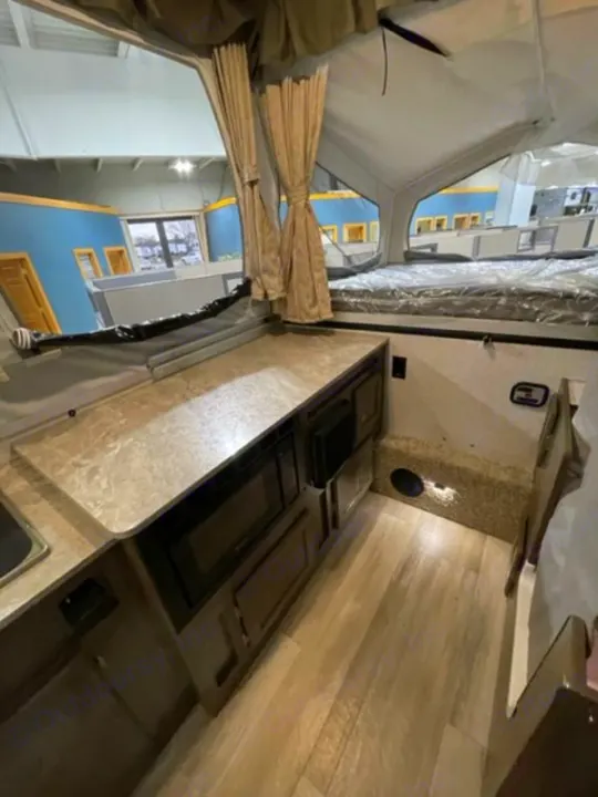 Cozy pop-up camper interior for your next RV rental. Features a compact kitchenette, two beds, and bright, airy space.. Forest River Rockwood Premier 2022