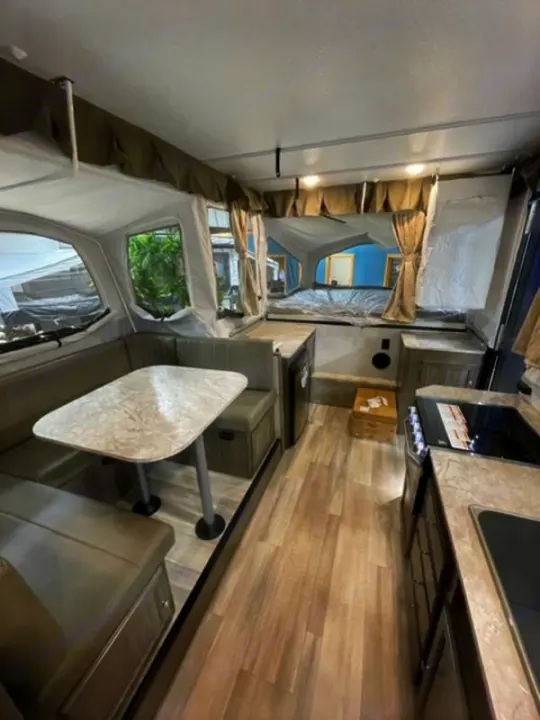 Spacious RV rental interior featuring a dinette, kitchen, and pop-out bed. Ideal camper for family trips.. Forest River Rockwood Premier 2022