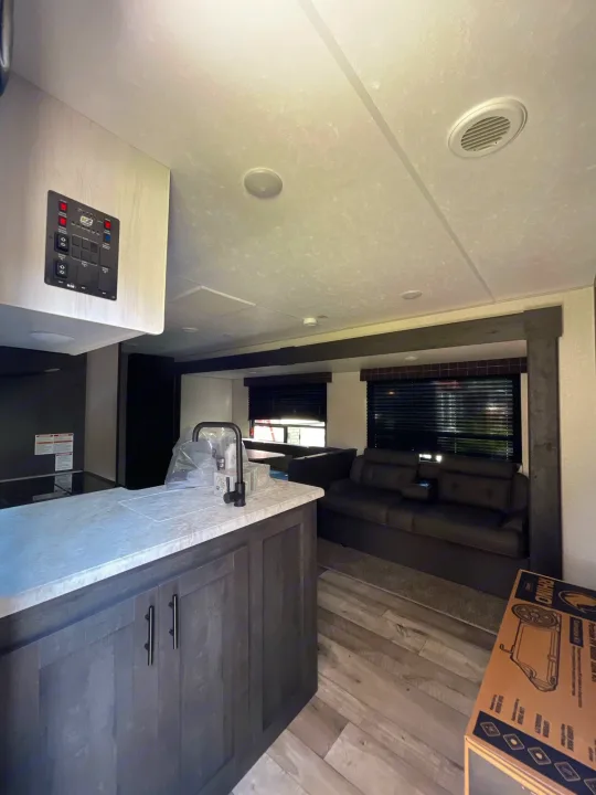 Modern RV rental interior with kitchen island, system control panel, and comfortable living area.. K-Z Manufacturing Sportsman Classic 2022