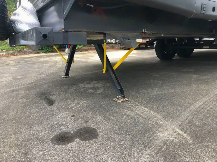 This RV rental's front PSx1 leveling jacks and yellow stabilizer bars are deployed on asphalt for stability.. Heartland RVs Prowler 2020