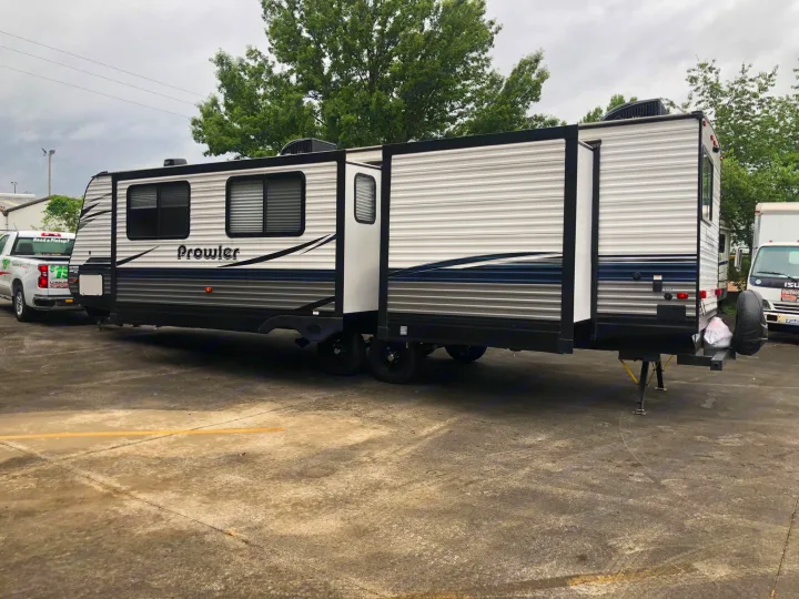 A large Prowler travel trailer RV rental with extended slide-outs, parked on a concrete lot.. Heartland RVs Prowler 2020
