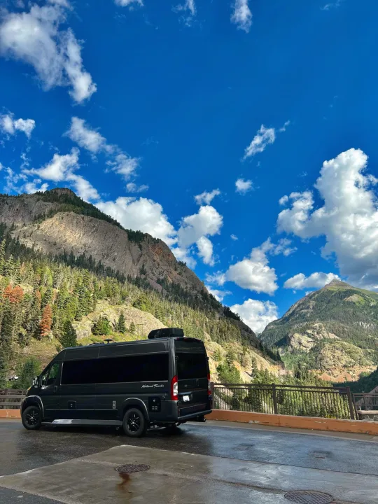 Black RV rental parked overlooking a scenic mountain valley with pine trees under a bright blue sky with clouds.. Dodge Other 2020