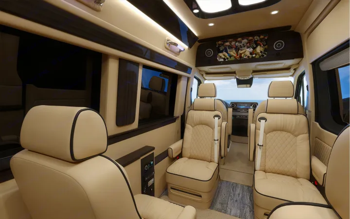 This luxury RV rental interior boasts cream leather captain's chairs, a large TV, and dark wood finishes.. Ultimate Toys Ultimate Coach 2023