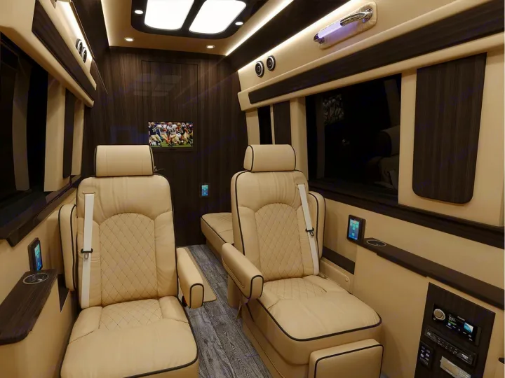 Premium rv rental interior with plush cream seating, wood accents, TV, and integrated controls for ultimate comfort.. Ultimate Toys Ultimate Coach 2023