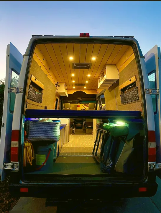 Spacious custom RV rental interior, seen from the rear. Features wood ceiling, kitchen, and ample storage.. Mercedes Sprinter 2005