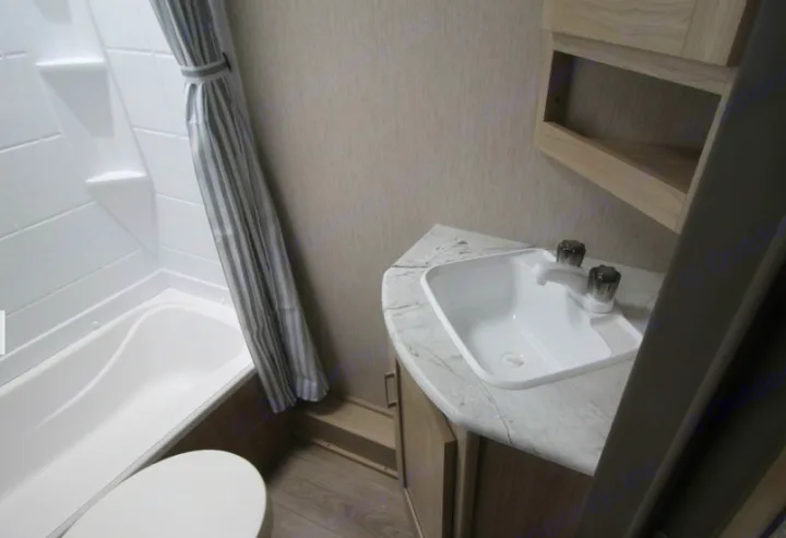 This RV rental features a compact bathroom with a shower/tub, toilet, and corner sink vanity.. Forest River Coachmen Freedom Express Ultra Lite 2020