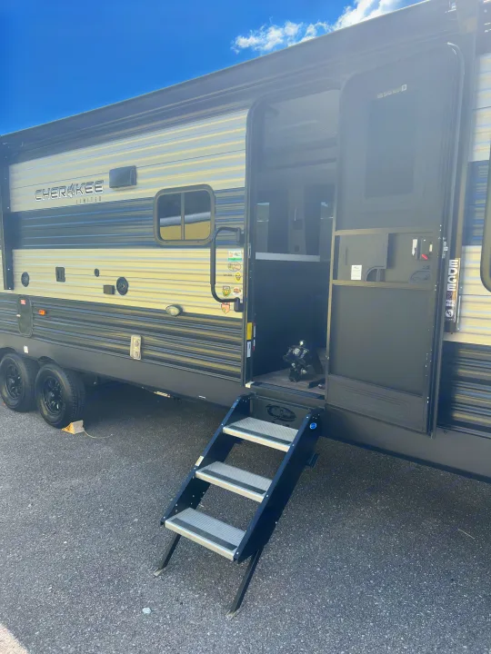 Explore the exterior of this Cherokee travel trailer RV rental, featuring an open door with extended steps on asphalt.. Forest River Cherokee 2021