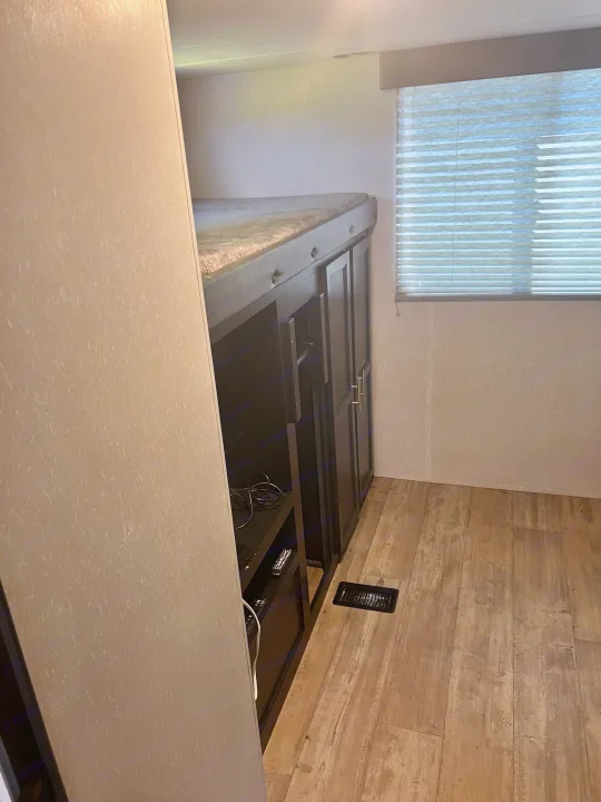 RV rental interior: cozy bunk bed over dark storage, window with blinds, and wood-look floor for comfortable travel.. Forest River Cherokee 2021
