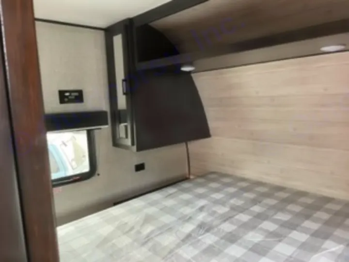 Explore the cozy bunk bed area of this RV rental, featuring a checkered ceiling, wood walls, and a side window for comfortable travel.. Jayco Jay Flight SLX 8 2023